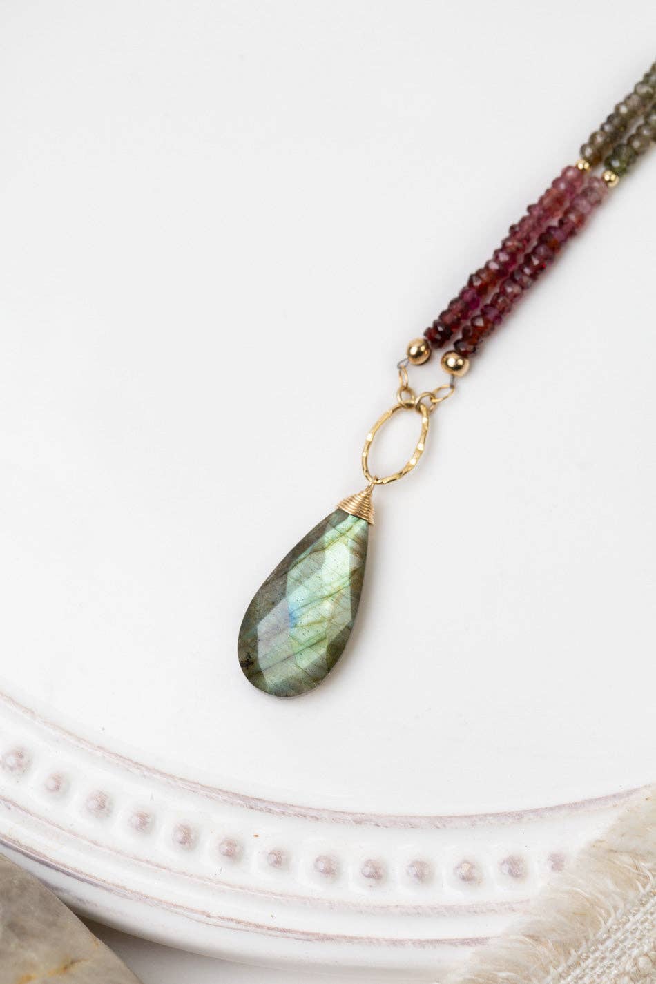 A close-up of the labradorite teardrop briolette pendant and faceted sapphire beads, emphasizing the intricate craftsmanship and luxurious materials.