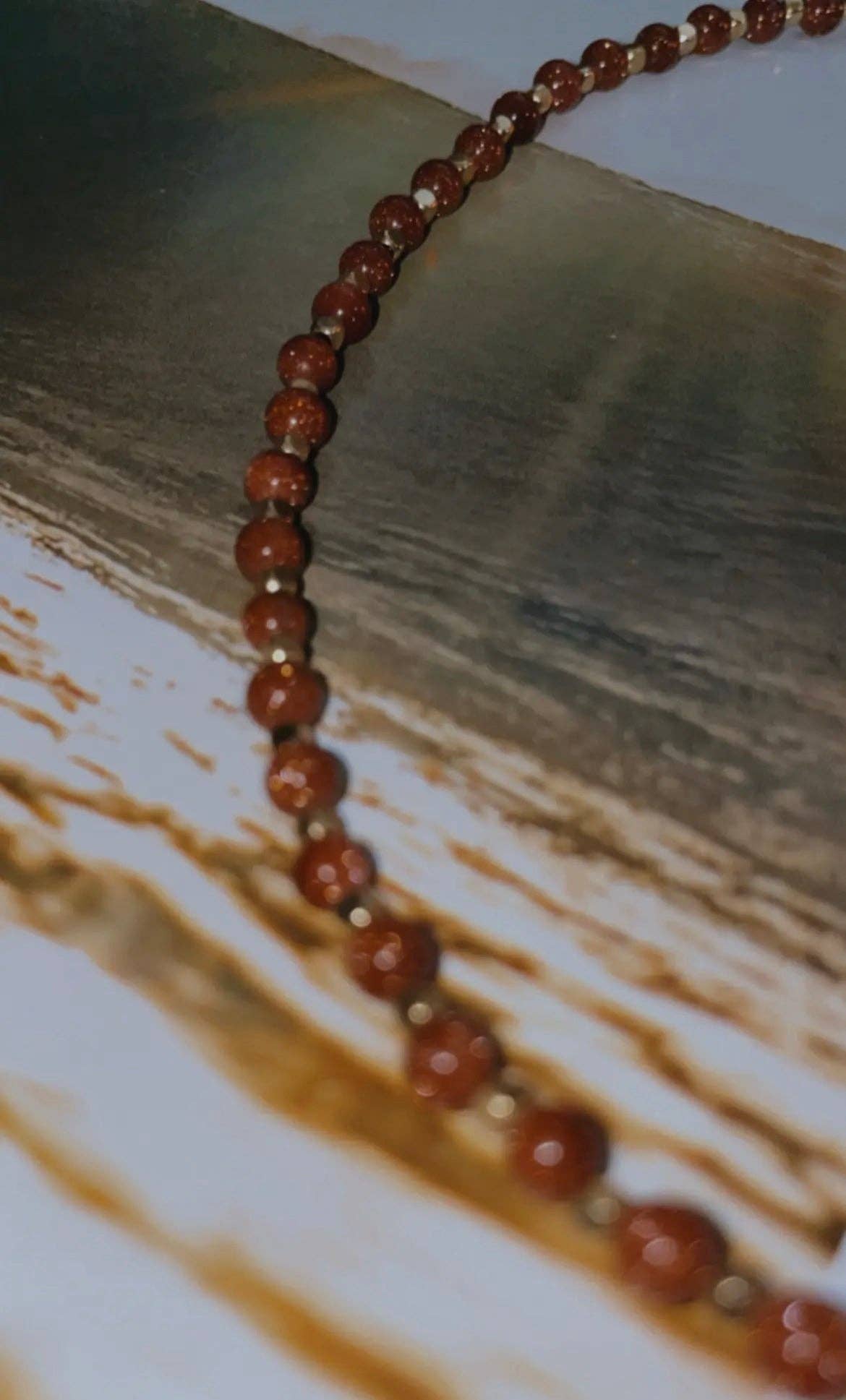 Close-up view of the Goldstone Choker Necklace, showing the sparkling goldstone beads and gold accents in detail.