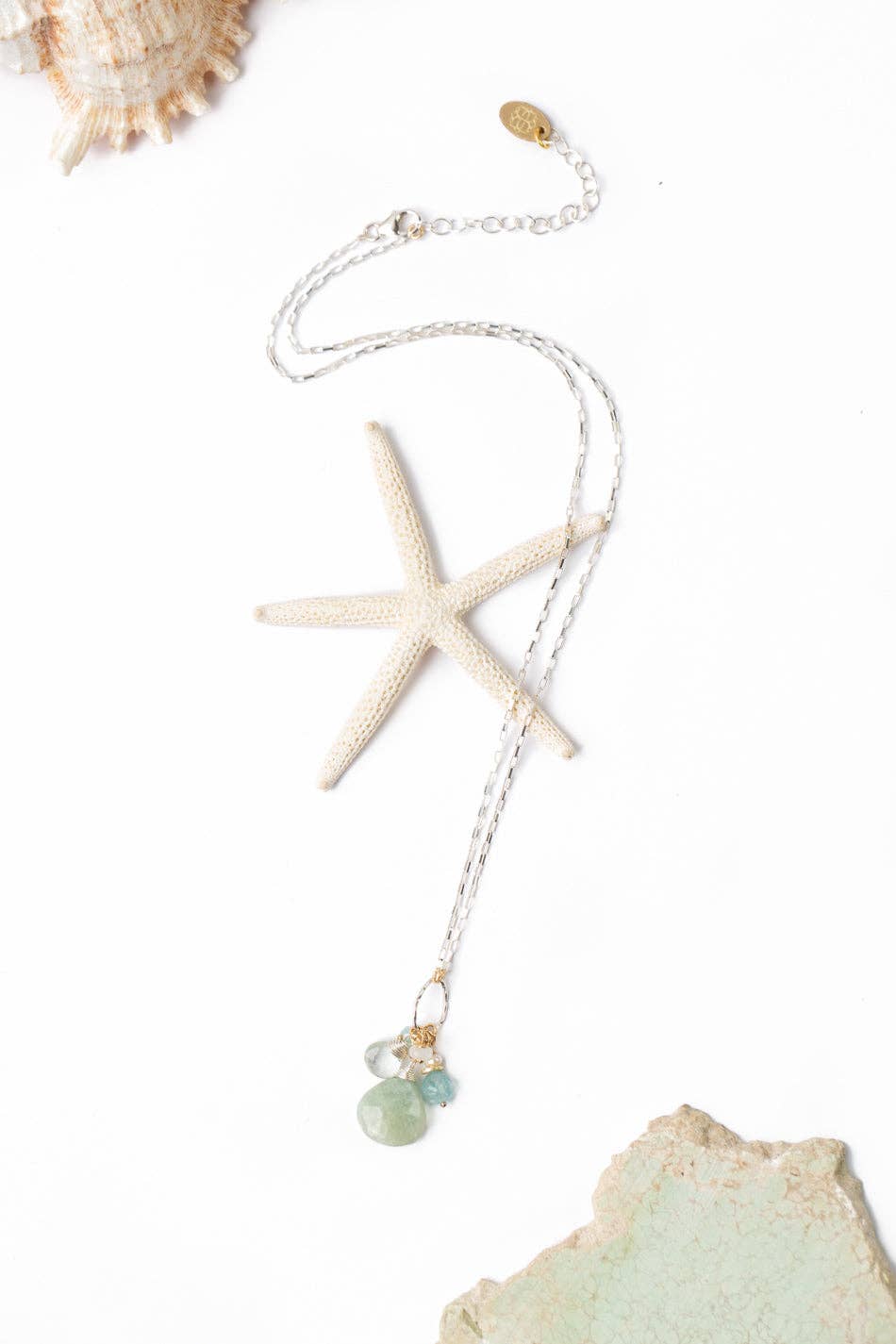 A Blue Apatite, Freshwater Pearl, and Green Amethyst Necklace featuring a hand-wrapped amazonite briolette, displayed on a white background with a starfish.