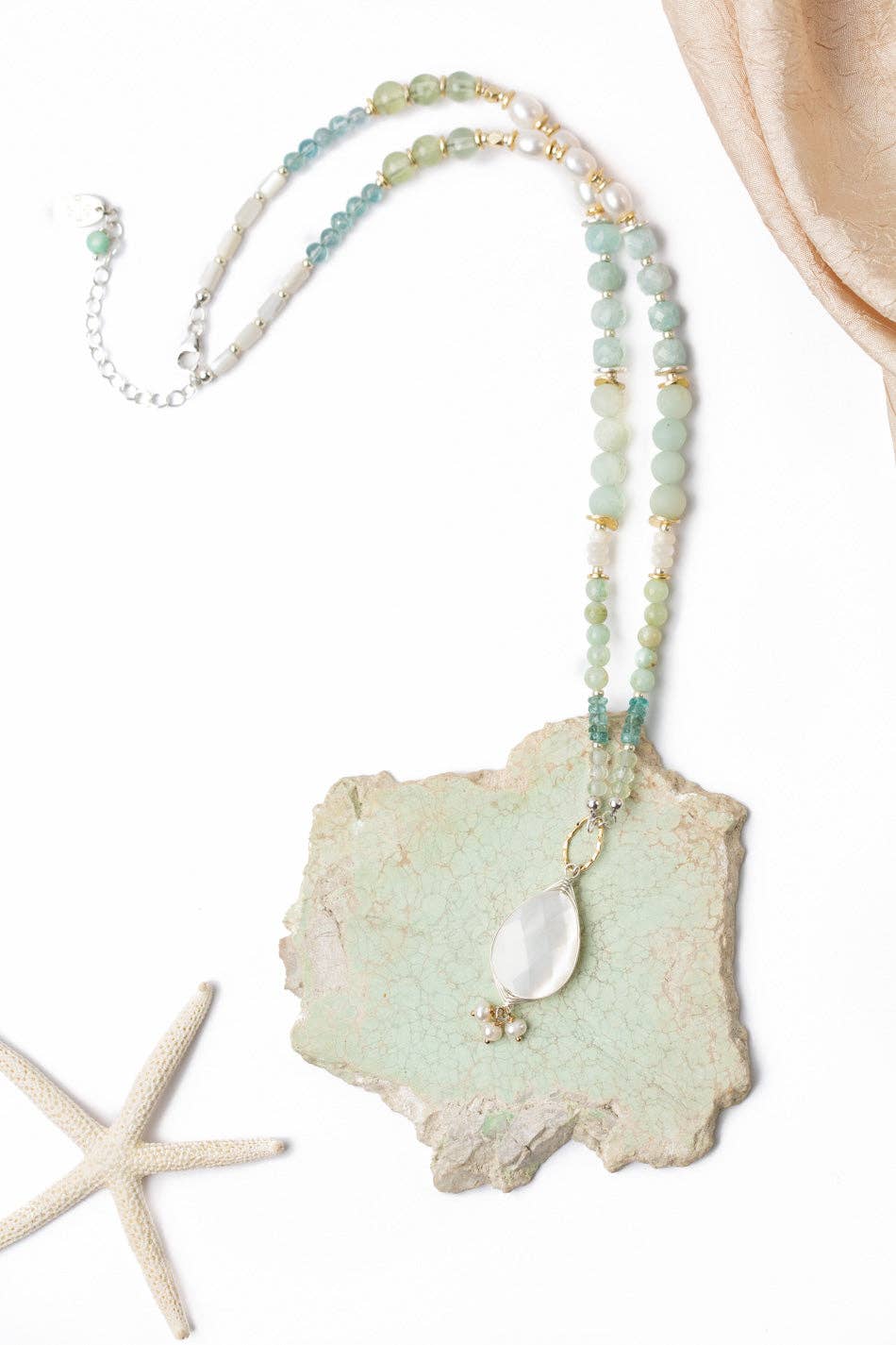 A Freshwater Pearl, Amazonite, and Blue Apatite Necklace featuring a mother of pearl pendant, displayed on a white background with a starfish.