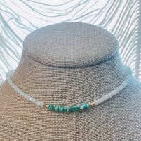 The Cove Choker featuring genuine rainbow moonstone and turquoise beads, displayed on a beige fabric bust, highlighting its adjustable 14-17 inch length and elegant design.