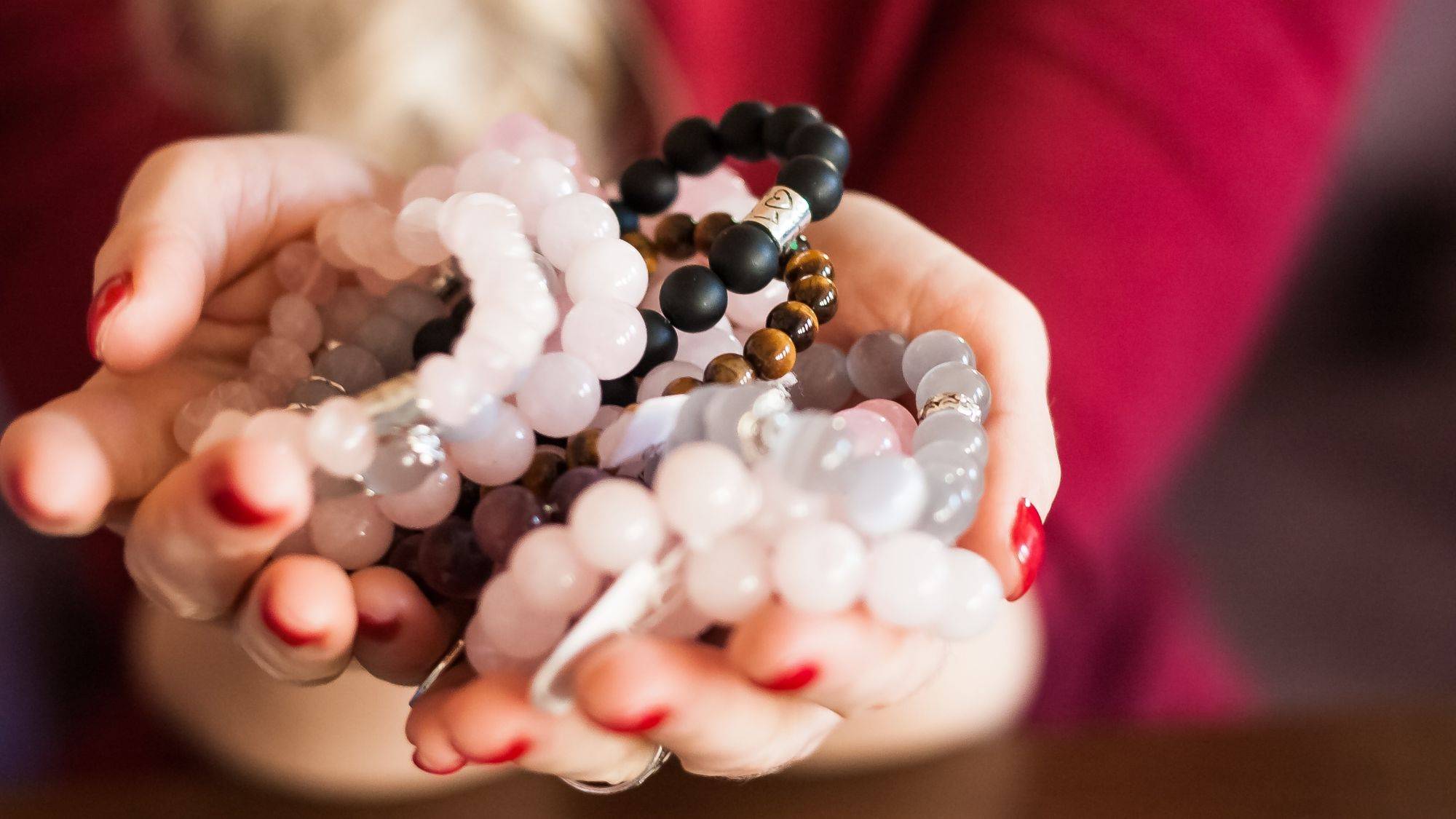 woman holding a handful of gemstone necklaces