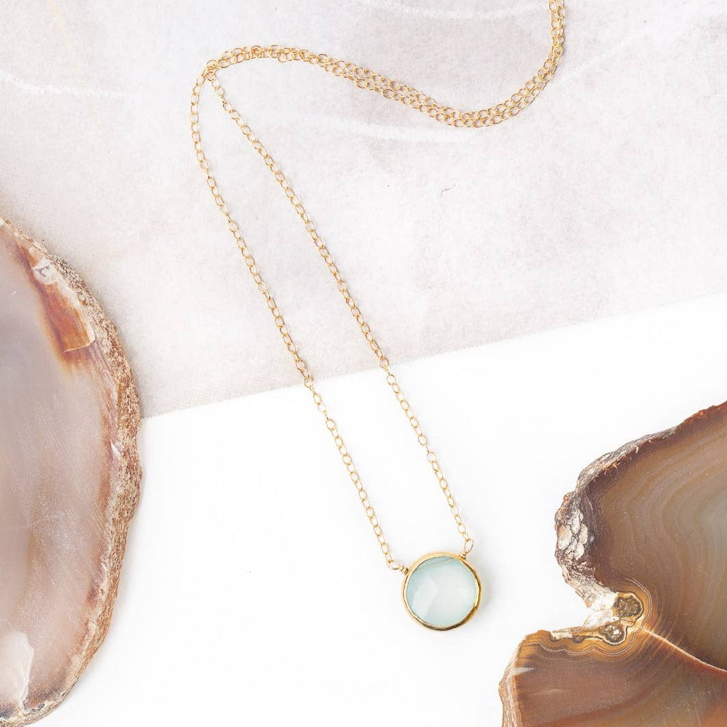 simple gold necklace with a single chalcedony stone